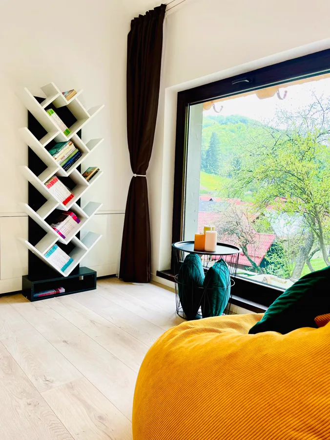 Reading nook with tree-shaped bookshelf and panoramic mountain view